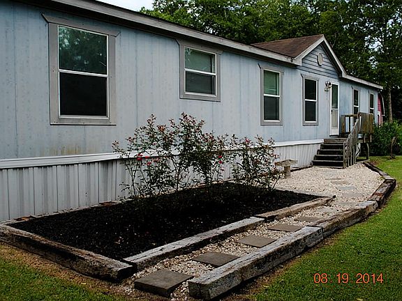 Lovely rose garden is surrounded by a white rock walkway that is bordered with hefty landscape timber