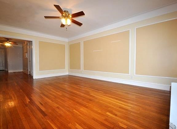 Large Sunny living room with a cove ceiling, wall and picture molding and refinished hardwood floors
