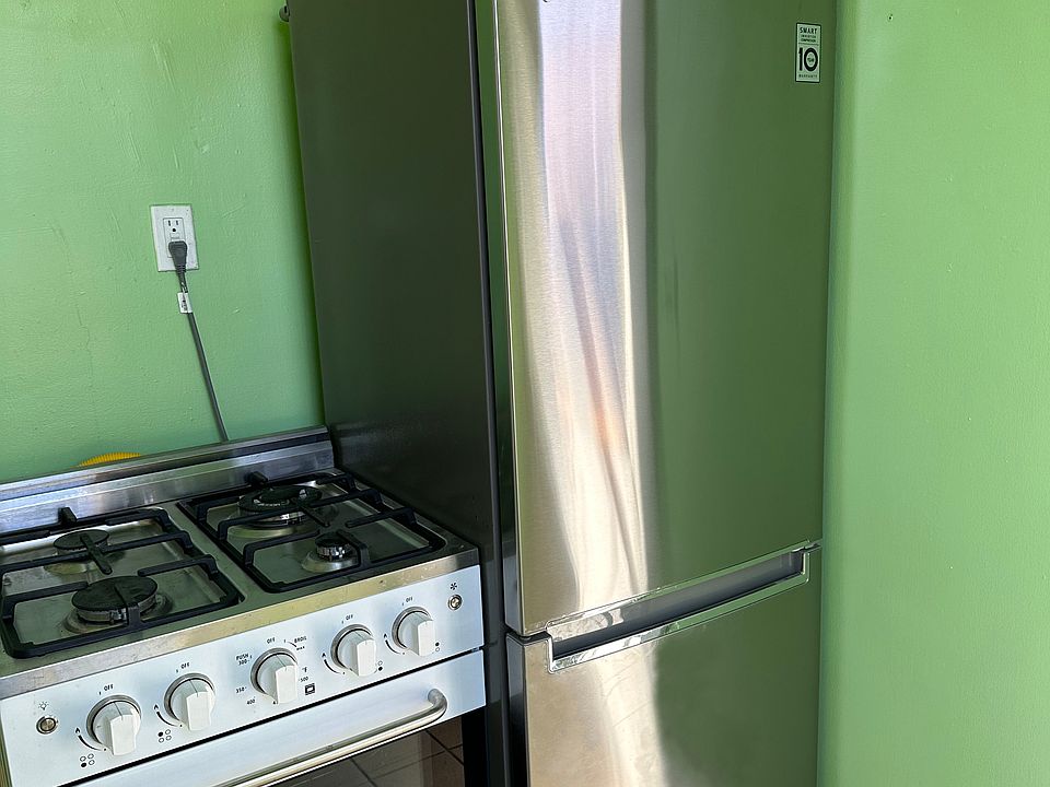 New range and stainless refrigerator in kitchen.