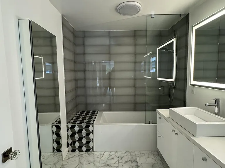 Primary bathroom features carrerra marble floors, bubble tub, shower and a toto heated toilet/bidet. Mirrored cabinet on the left is built into the wall for ample storage