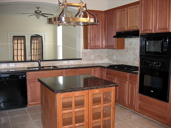 Kitchen has granite counter tops, tile back splash, and island
