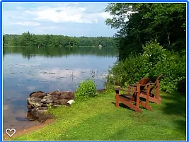 Looking across lake at the island. Picnic table to right of chairs.