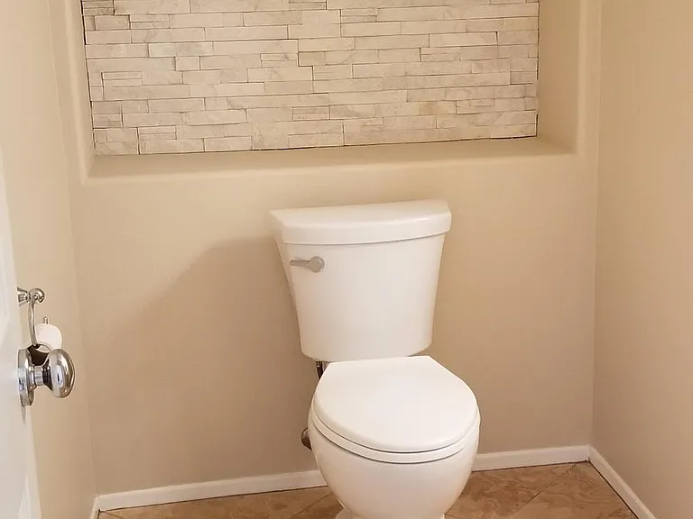 Downstairs 1/2 bath with stone wall cut out, pedestal sink, and Peruvian Travertine tile floors.