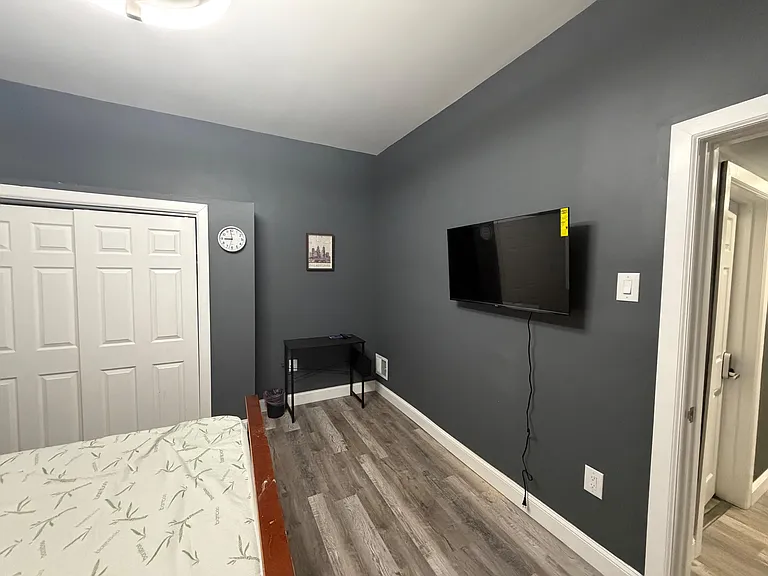 Private bedroom with wood-look flooring, a closet, and a wall-mounted TV with space for a small desk or dresser.