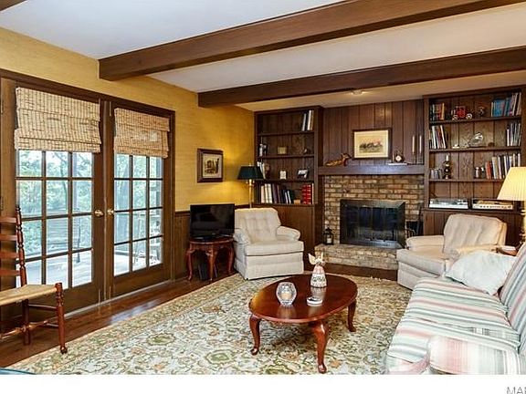 Main floor family room with hardwood floors, w/b fireplace, built in book cases and double doors to nice screen porch.