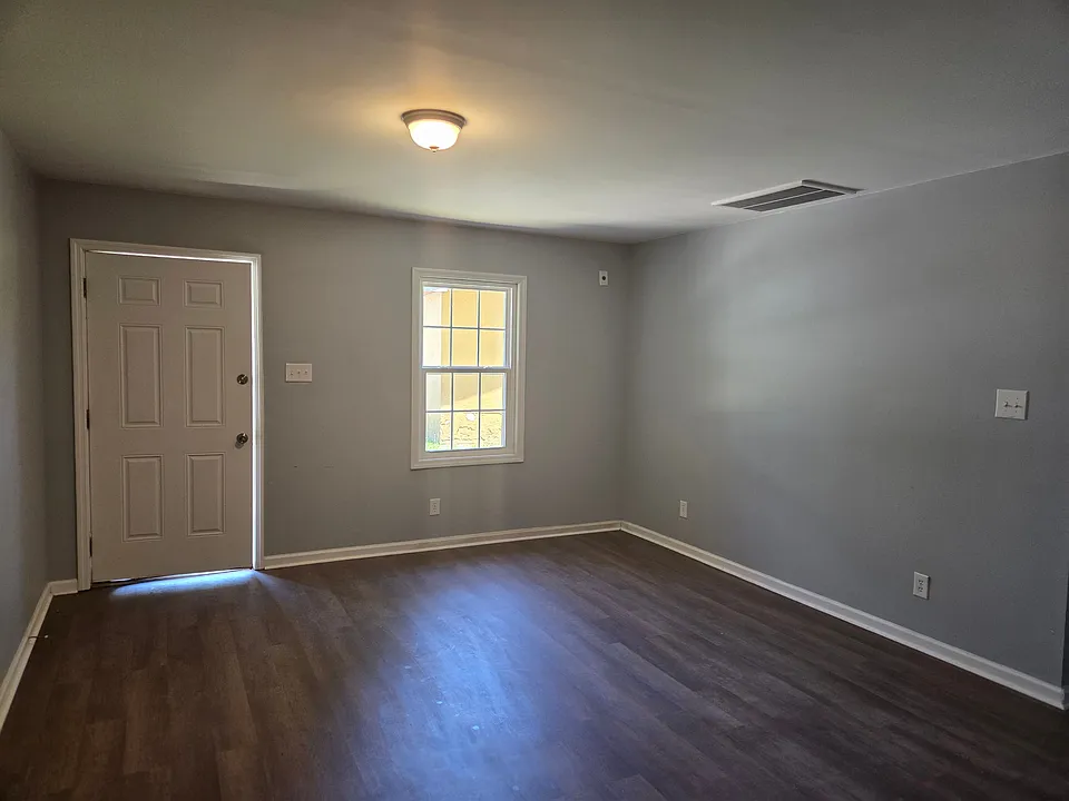 Welcome into a bright and spacious living room designed for comfort and flexibility. Featuring durable wood-style flooring, modern neutral paint, and abundant natural light, this inviting space offers plenty of room for relaxing, entertaining, or creating