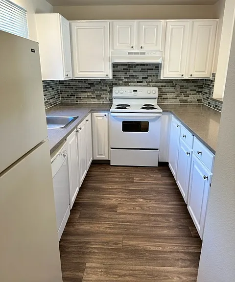 Updated kitchen with new counters and tile backsplash, white cabinetry, and vinyl plank flooring.