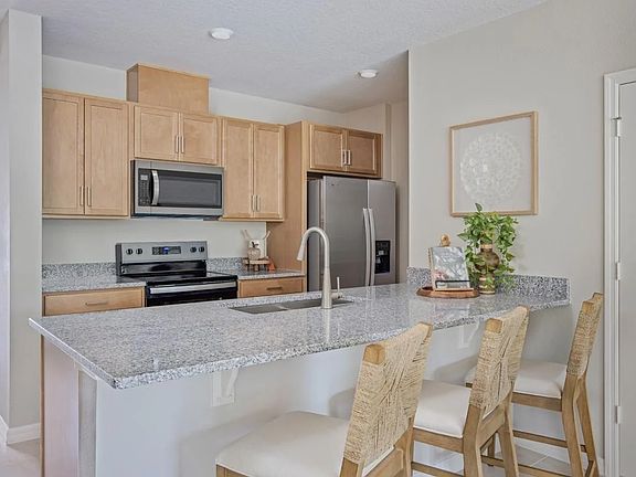 Modern kitchen with granite countertops, stainless steel appliances, breakfast bar seating, and open layout overlooking the living and dining areas.