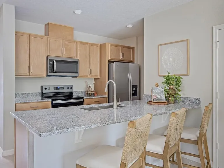Modern kitchen with granite countertops, stainless steel appliances, breakfast bar seating, and open layout overlooking the living and dining areas.