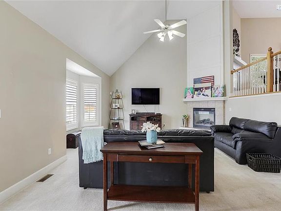 Enter to the light and bright living room with soaring ceilings, fireplace, and new plantation shutters