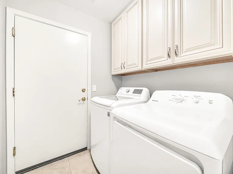 Laundry room leading into double garage. Garage has ample cabinet storage, a water heater, and a new soft water conditioning system.