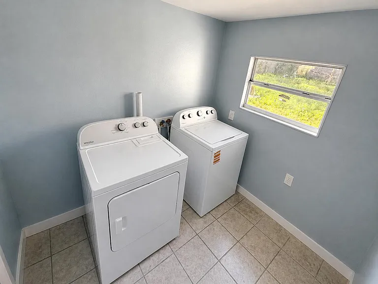 Dedicated laundry room with washer/dryer hookups, tiled flooring, and a window for ventilation and natural light.