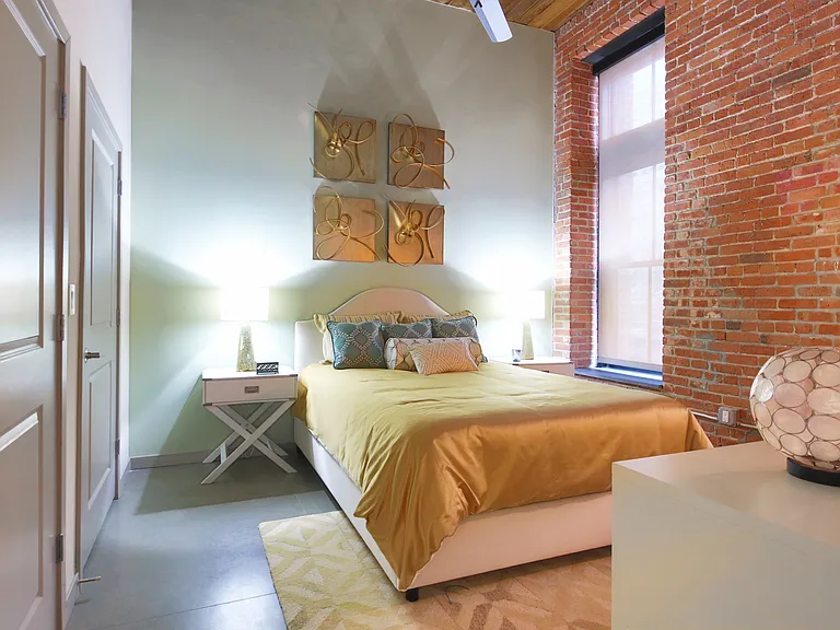 Exposed Brick from the Original Building Enhances the Bedroom