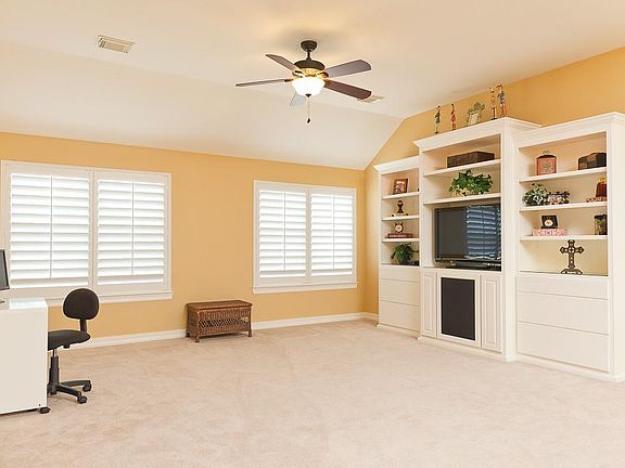 The large gameroom has a built-in entertainment center with lights, updated ceiling fan and plantation shutters.