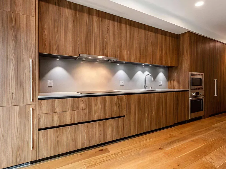 Apartment Kitchen with Wood Cabinets, Cooktop, and Under-Cabinet Lighting