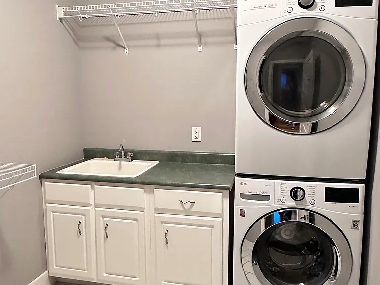 Second floor laundry room with a sink and plenty of storage and hanging space.
