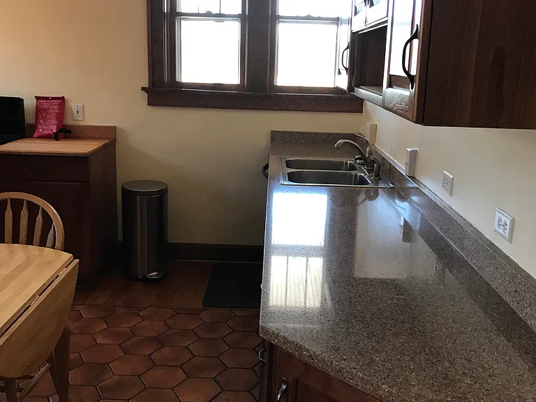 another kitchen view, small balcony behind windows, trash and recycling bins optional. no garbage disposal.