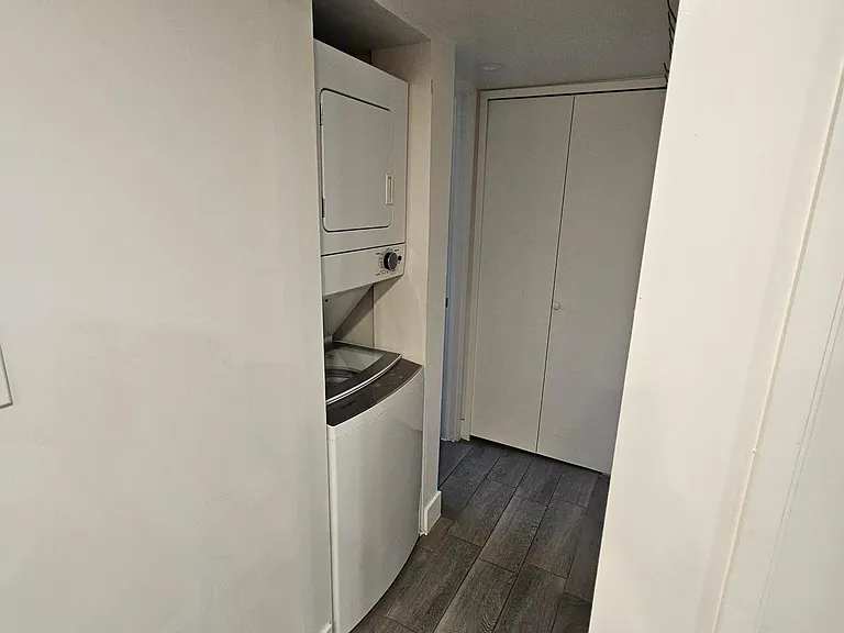 Hallway to the bathroom with small storage closet, washer and dryer.