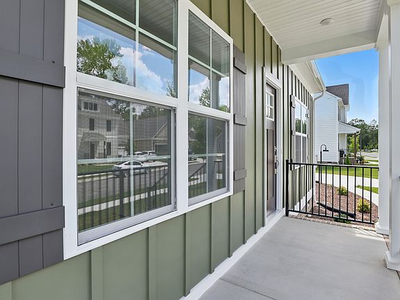 Green house front porch with windows and black railing in Poplar Village, overlooking The Charles an