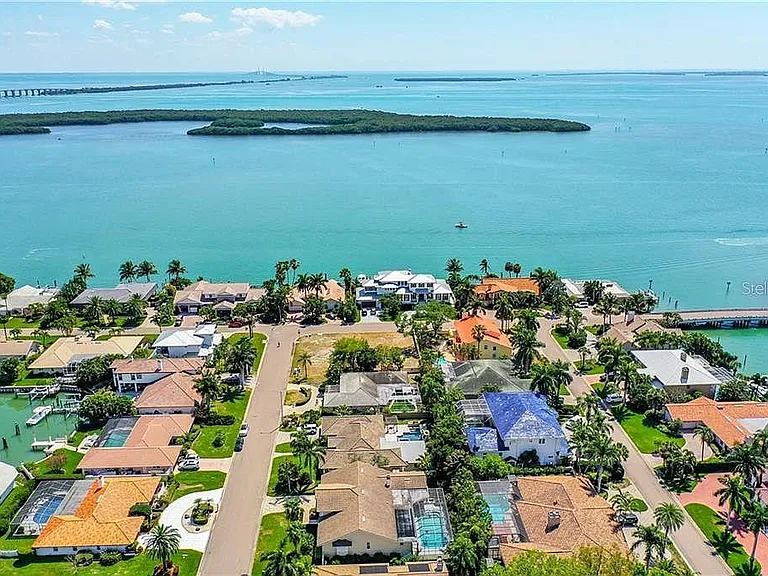 house with orange roof and vacant lot behind it. 2nd from the right water, and 2nd from south across from the multi level white house by the water.