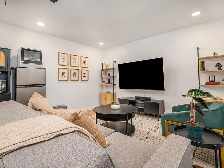 Shared lounge with comfortable seating, large wall-mounted TV, and shelvingideal for relaxing or gathering with housemates.