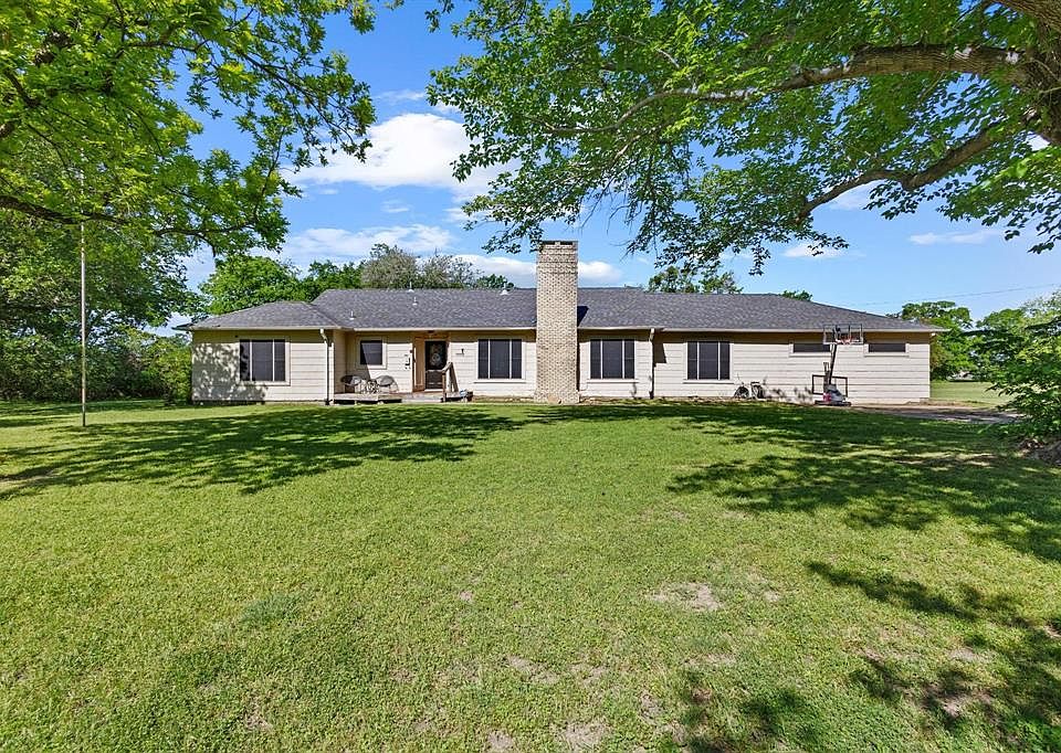Rear view of property featuring a chimney, a yard, and a patio