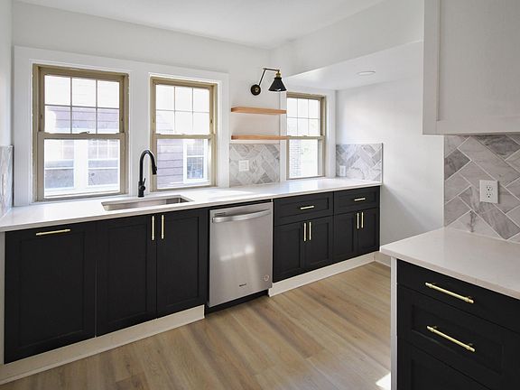 Modern kitchen with brand new stainless steel appliances including electric stove, refrigerator, microwave and dishwasher