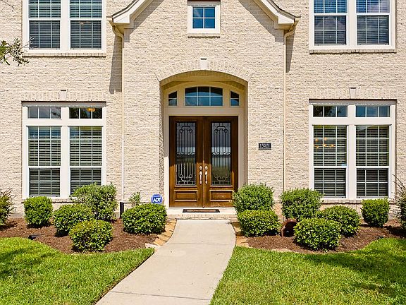 An arched porch with beautifully wood stained double entry doors with transom, flanked by beveled pr