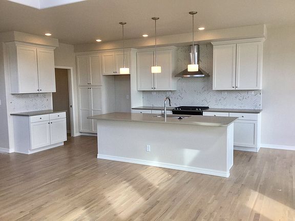 Beautiful spacious kitchen with large island, Quartz - Ash Gray counter tops, herringbone mosaic back splash, white Maple cabinetry and stainless steel appliance package (including gas range)! (Photo of home under construction)