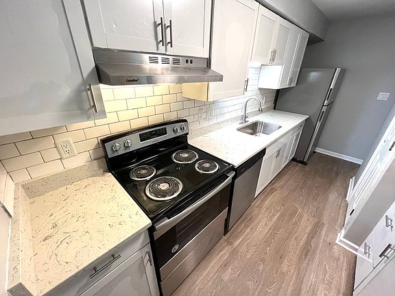 Bright white kitchen with stainless steel appliances, shaker cabinets and quartz countertops