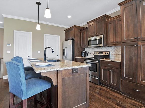 Additional view of the kitchen that shows the clean lines of the stained cabinets and the upgraded tile work with herringbone pattern and stainless steel appliances. Large walk-in pantry and laundry room are also shown in this photo.