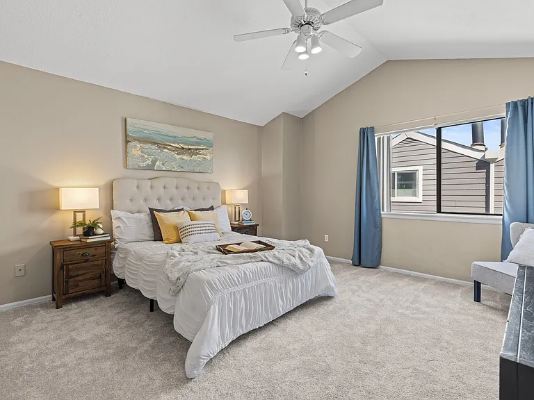 Spacious primary suite featuring vaulted ceilings, overhead lighting and ceiling fan, and plenty of room for a king-sized bed.