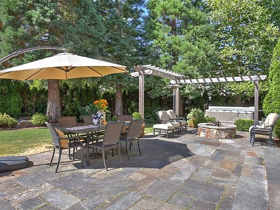 Outdoor living at its finest with slate patio framed by a pergola enjoys a hot tub & landscape lighting.