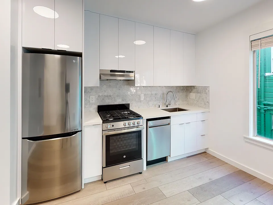Kitchen with multiple cabinets, refrigerator, stove, range hood, and sink