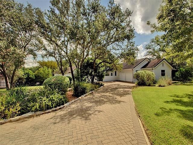 Mature oaks line the pavered driveway.