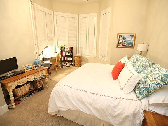 Large master bedroom holds king bed with rounded window alco