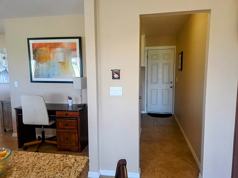 Desk area across from kitchen island, and door leading to garage.