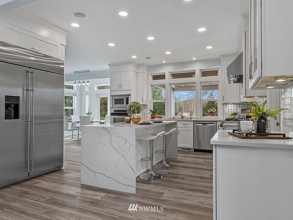 Professional kitchen with quartz waterfall island, professional stainless steel appliances, 48" built-in refrigerator.