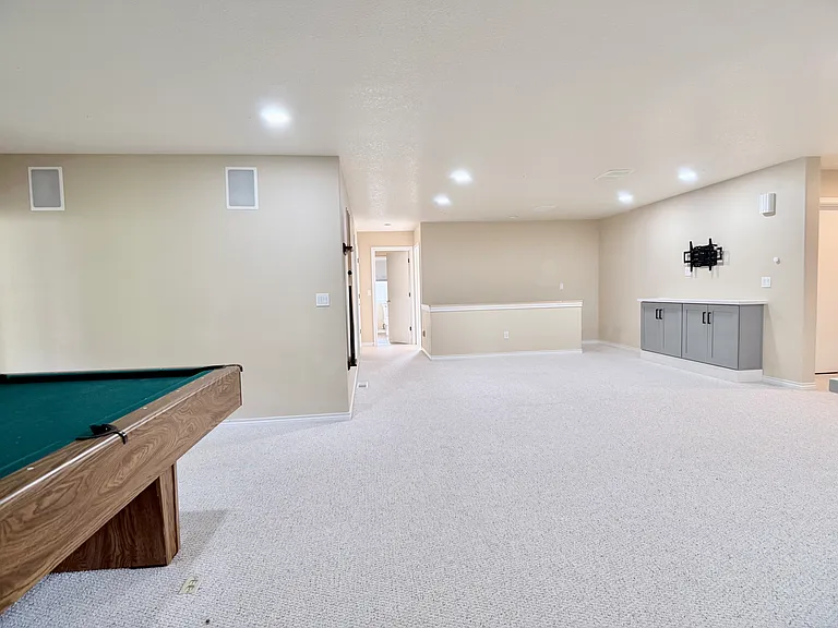 Alternate view of the lower-level living area, highlighting custom built-ins and a dedicated TV mount for a seamless entertainment setup.