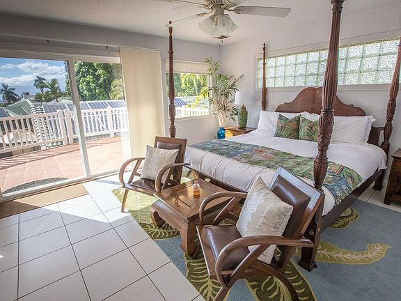 Main house master bedroom with private entrance and lanai. King bed, central AC, ceiling fans, TV, walk-in closet.