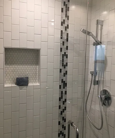 Unit 11 shower includes niche & gray mosaic accent tile.