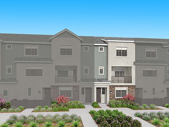 A multi-story residential building with a landscaped front yard, surrounded by a clear blue sky.