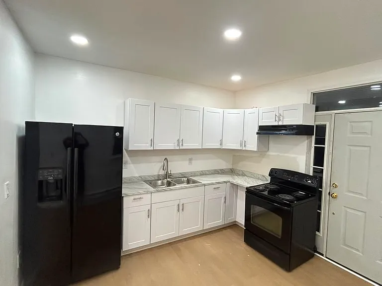 Fully renovated kitchen with fridge and electric stove/oven.