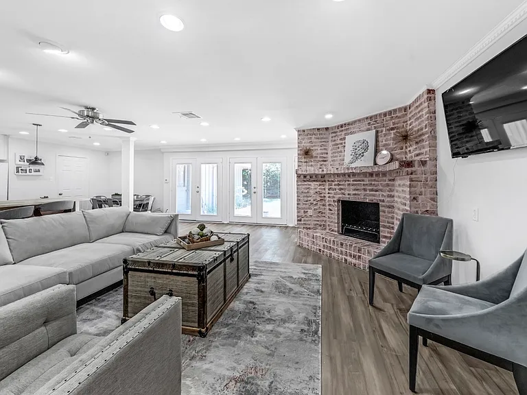 Welcome to the living room with a cozy fireplace, furnished by West Elm, large tv and access to the yard. This open space is so great for gathering on movie night or casual dinner