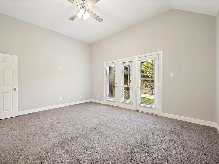 Spacious room featuring vaulted ceilings, a ceiling fan, and gray carpeting