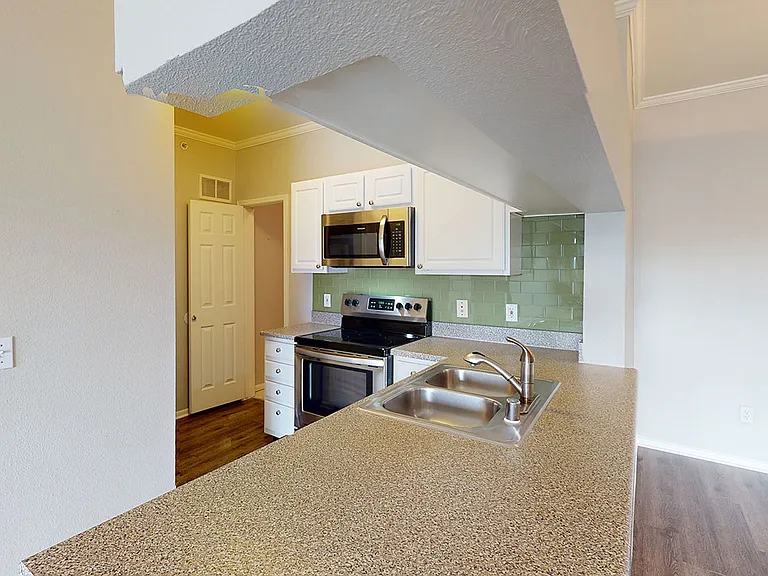 Apartment kitchen with wood-style flooring.