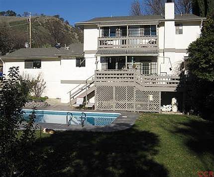 Back of the house showing the decks, with the built in vinyl lined pool. There is room for storage u