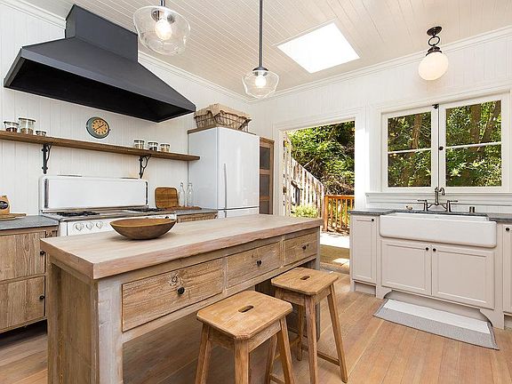 Fully stocked kitchen with new Fisher Paykel refrigerator, Kohler farmhouse sink, Kitchen Aid dishwasher, and restored gas Wedgewood range. Kitchen double doors open to dining deck.