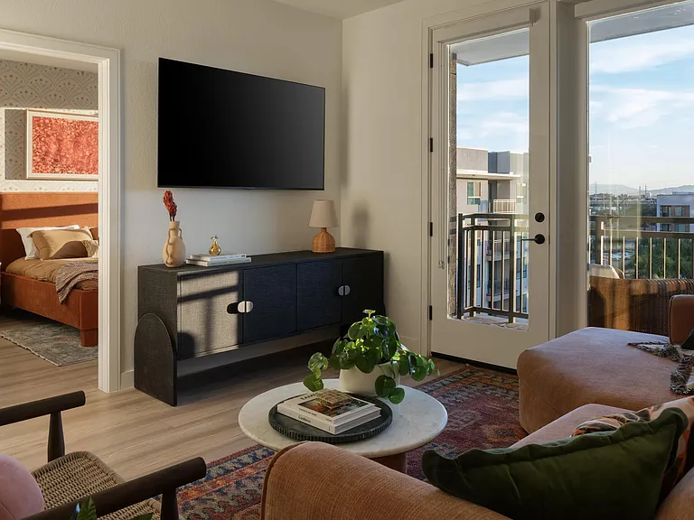 A sunlit living space with warm textures, layered tones, and balcony views that extend your living area outdoors.