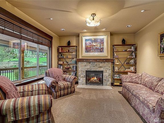 Living Room with Montana Rubble Stone gas fireplace. Large windows overlook the covered porch and nature beyond.